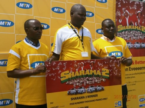 Umukozi wa MTN (hagati) ashyikiriza abanyamahirwe batsindiye ibihumbi 500 sheke zabo.