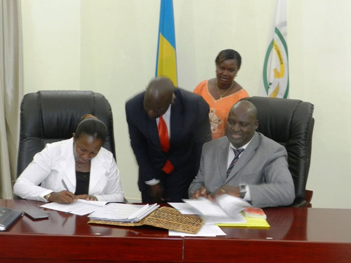 Guverineri w'Intara y'Iburasirazuba, Mme Uwamariya Odette (ibumoso) na Perezida w'Inteko y'Intara ya Trans Nzoia, Hon. David Kinisu Sifuna, basinya amasezerano. Abahagaze ni abahamya.