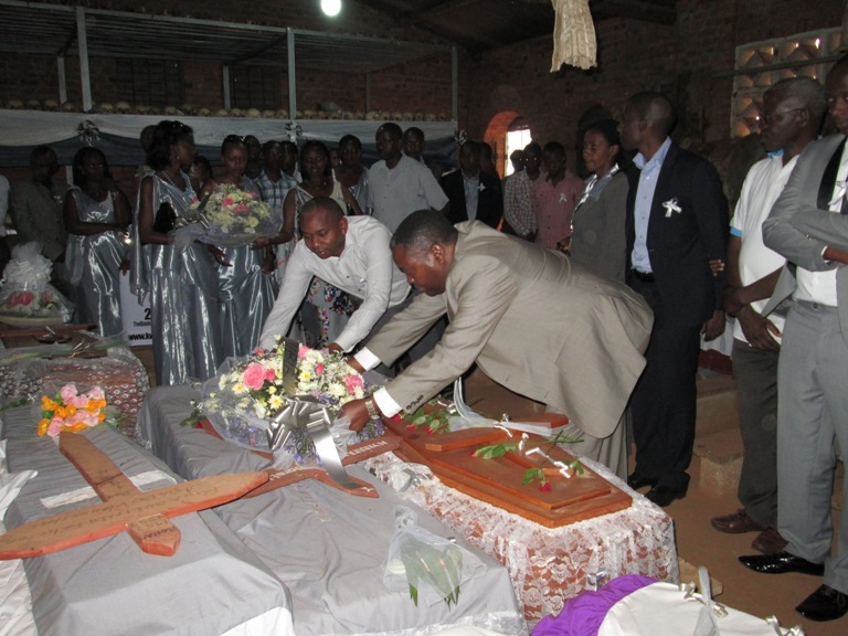 Nyoni, umuyobozi mukuru wa MAGERWA ashyira indabo ku mva zirimo imibiri.