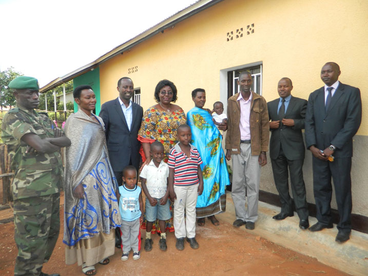Imiryango ibiri icumbitse muri Rukoma iri kumwe n'abayobozi imbere y'inzu bubakiwe.