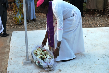 Mgr Smaragde nyuma y'igitambo cya misa yifatanije n'abaganga ashyira indabo ku mva.