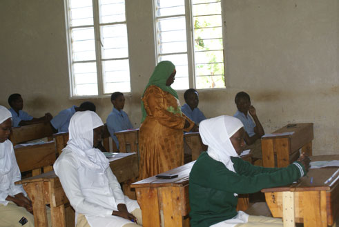 Umwarimu agenzura ko abanyeshuri bujuje ibisabwa ngo bitabire ikizamini.
