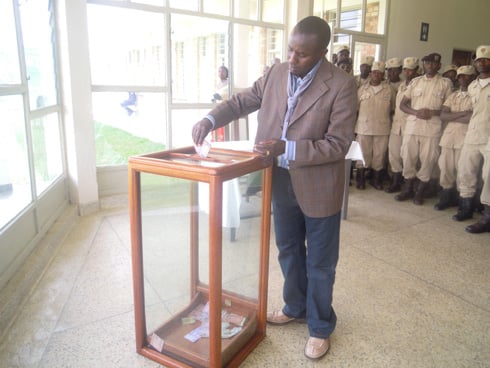 Umwe mu bakozi ba gereza ya Muhanga ashyira inkunga mu gasanduku kabugenewe.