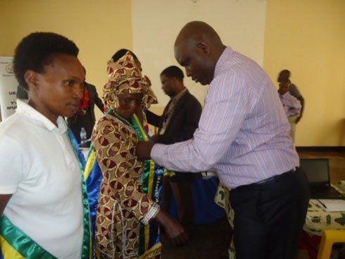 Uhagarariye abunzi muri MINIJUST yambika abunzi umwambaro bari bahawe.