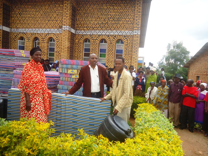 Umushumba w'Itorero 'Evangelical Restauration Church', Bishop Gasore Constantin (hagati) ashyikiriza ibikoresho umwe mu banyeshuri.