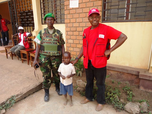 Umwe mu ngabo za RDF ashyikiriza umwana abakozi ba Croix Rouge.