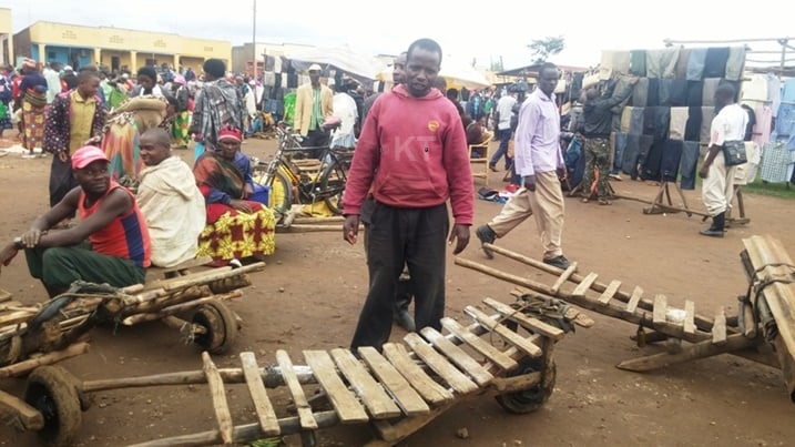 Aha ni mu isoko rya Rugarama, Ntawizera arindiriye abamuha akazi ko gutwara imizigo.