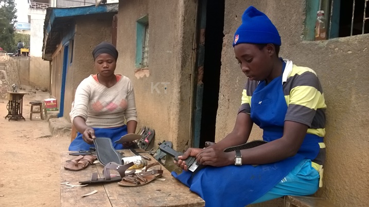Aba bakobwa bari mu kazi ko gutunganya inkweto. Nta bute bagira kuri uyu murimo.