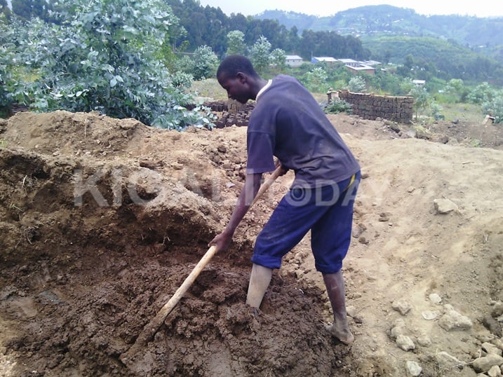 Habimana, umwana w'imyaka 15 arimo gukata icyondo cyo kubumbamo amatafari yo kugurisha.