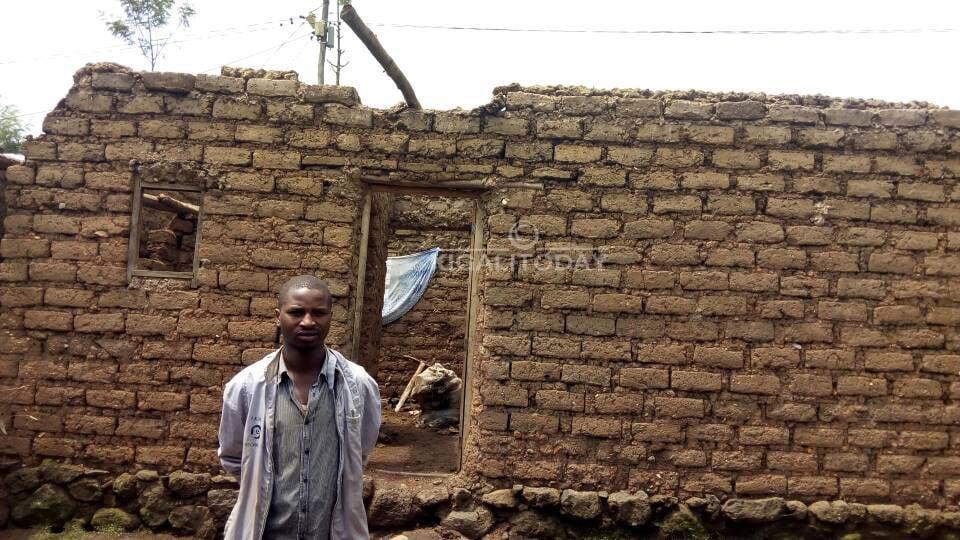 Uyu mugabo ahagaze imbere y'inzu ye yasenyutse 