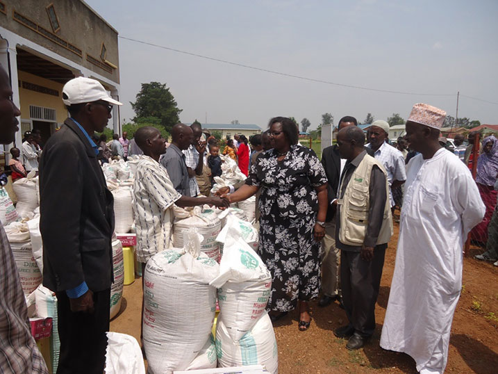 Minisitiri Mukantabana n'Umuyobozi wa Direct Aid bashyikiriza abanyarwanda birukanywe muri Tanzaniya inkunga babazaniye.