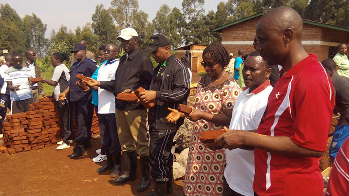 Minisitiri w'Intebe, Anastase Murekezi ahererekanya amatafari n'abaturage mu rwego rwo kwihutisha akazi.