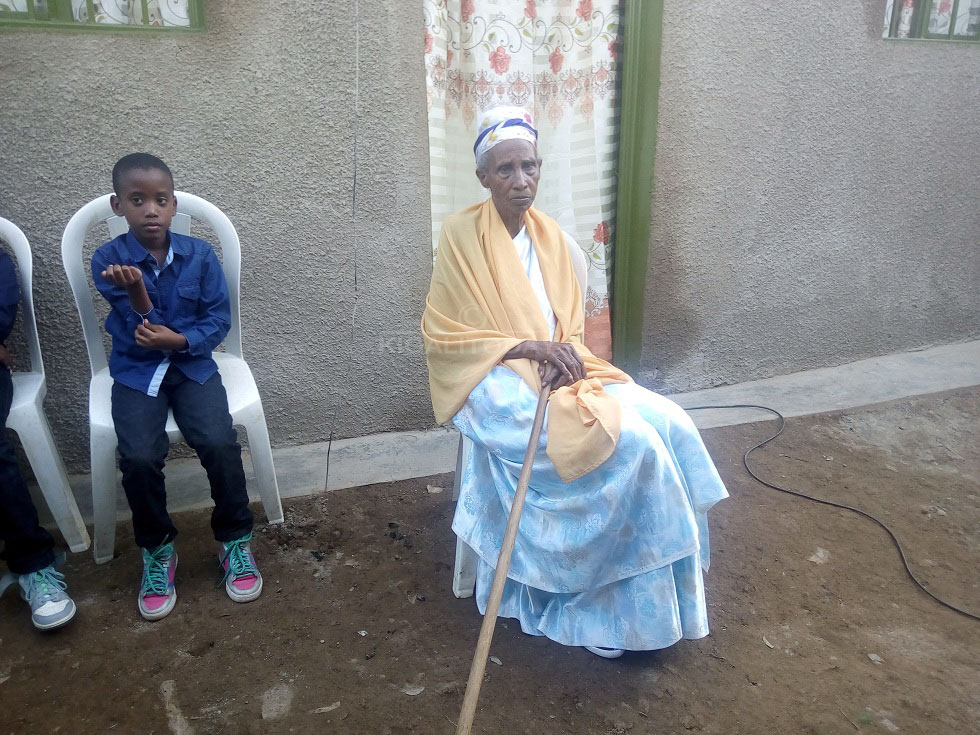 Mukecuru Musanabera yicaye imbere y'inzu ye bamusaniye 