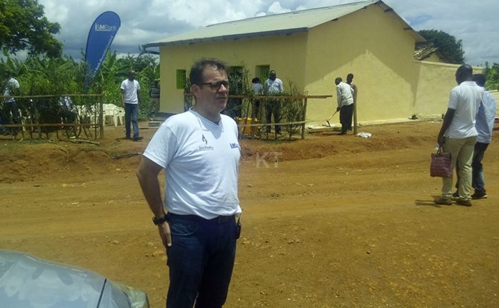 Umuyobozi wa I&M Bank, Robin Bairstow, imbere y'inzu y'umukecuru bamaze gusiga irangi.