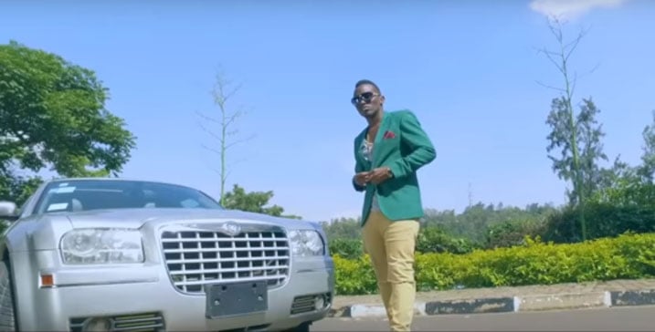 Tom Close mu mashusho y'indirimbo "Ferrari", aba ahagaze imbere y'imodoka nziza izwi nka Chrysler.