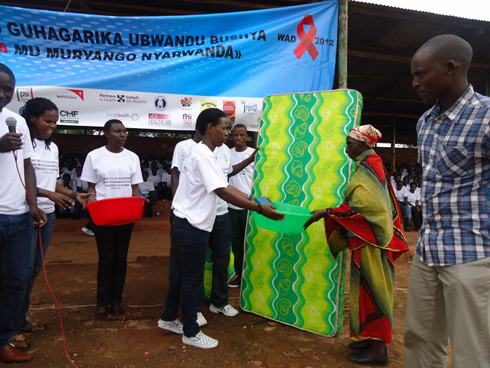 Umukecuru ashyikirizwa matera yahawe n'intore z'abanyeshuri.