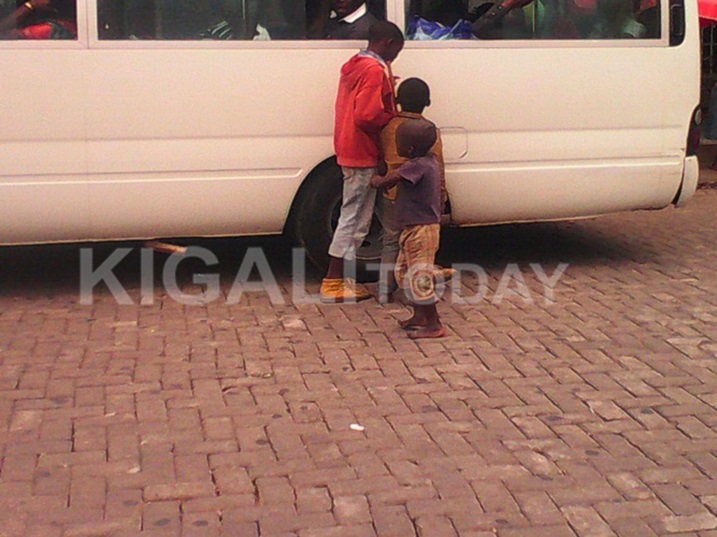 Ubasanga ku modoka babyiganira mu bagenzi babasaba uducupa bamazemo amazi.