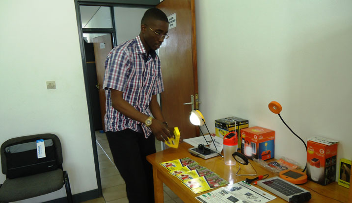 Umukozi wa SNV agaragaza amatara y'imirasire y'izuba ahendukiye abaturage, bakaba banayasharijaho telefone.