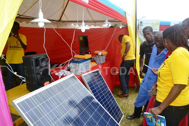 Umukozi wa Sosiyete ya Mobisol icuruza ingufu ziva ku zuba (ufite ikayi) asobanurira umuturage ko ashobora gukoresha imirasire y'izuba akabona urumuri kandi agakora n'indi mirimo.