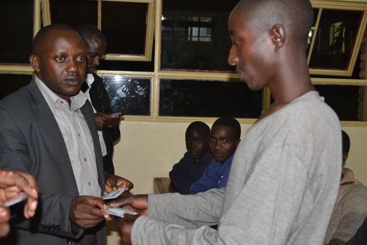 Kizito yahaye aba banyeshuri bashya amakarita y'ishuri nk'ikimenyetso cyo gutangira amasomo.