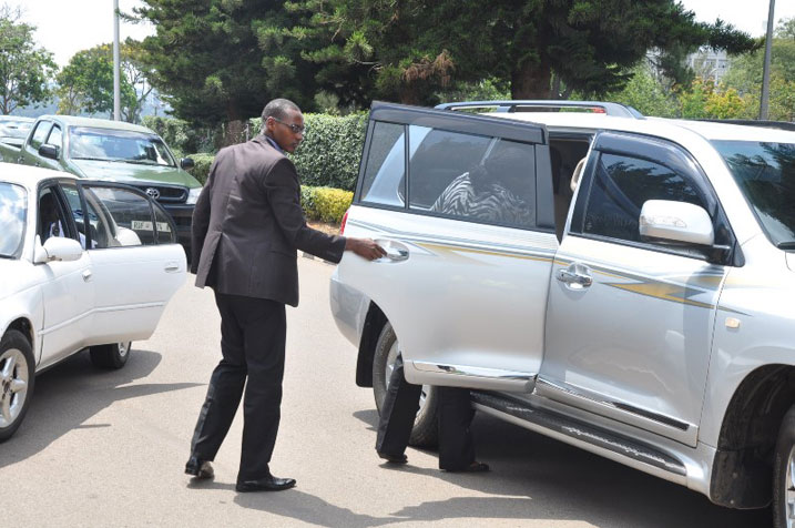 Minisitiri w'ubuhinzi n'ubworozi arimo gufata igikapu mu modoka ye mbere yo kujya muri bisi.