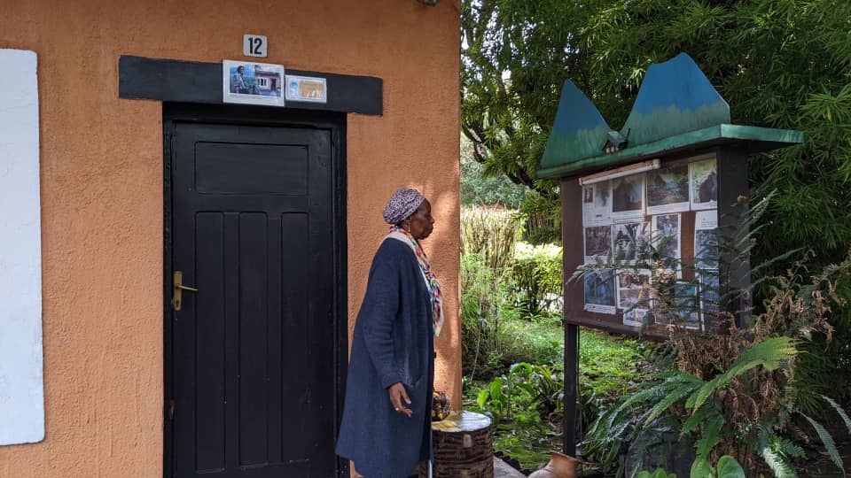 Rusingizandekwe Gaudence, ahagaze imbere y'icyumba Dian Fossey yararagamo ubwo yabaga yaje mu Rwanda kuhakorera ubushakashatsi ku mibereho y'Ingagi